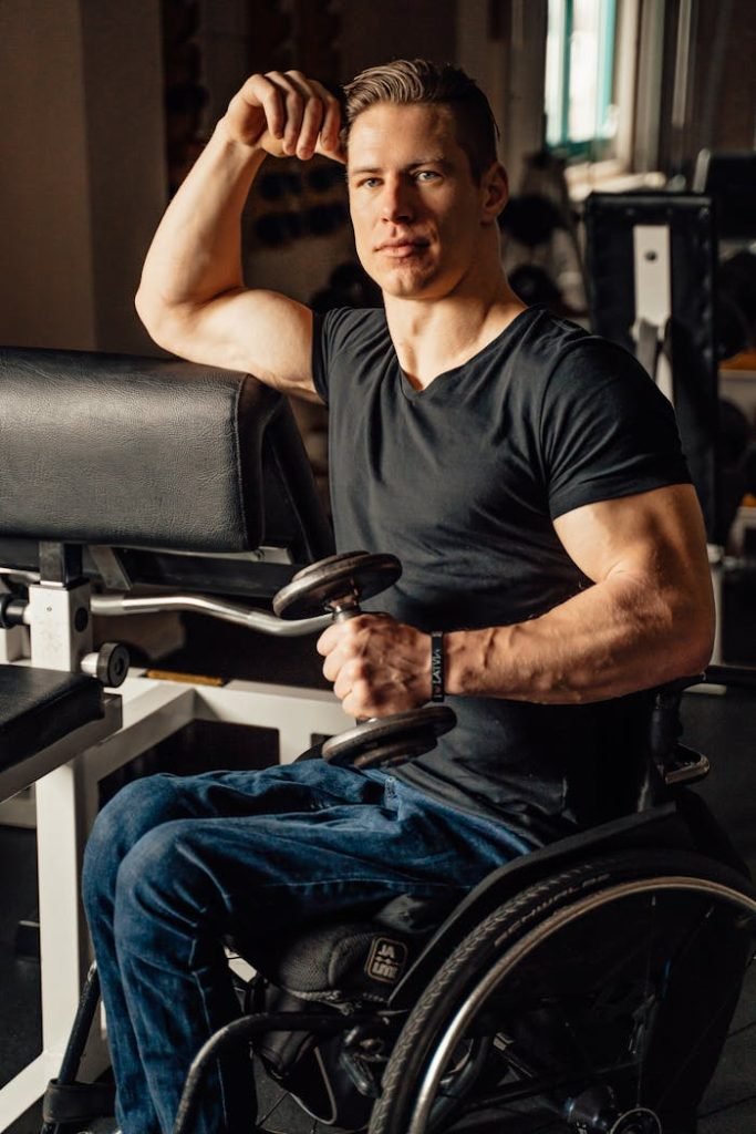 Man in a wheelchair lifts weights, showcasing strength and determination.